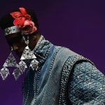 Stylish portrait featuring bold fashion with denim and floral headband on vibrant purple background.